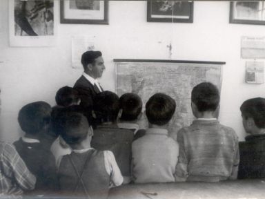 Fotografía antigüa de mestro impartiendo clase a sus alumnos