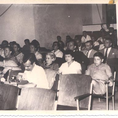 Fotografía antigüa de personas sentadas en salón de actos