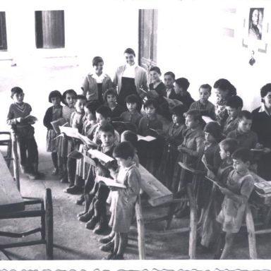 Fotografía antigüa de niños en clase leyendo 