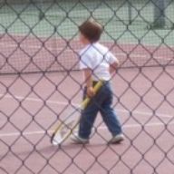 Niño jugando al tenis en pista