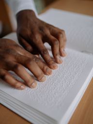 Foto de persona leyendo libro en braille